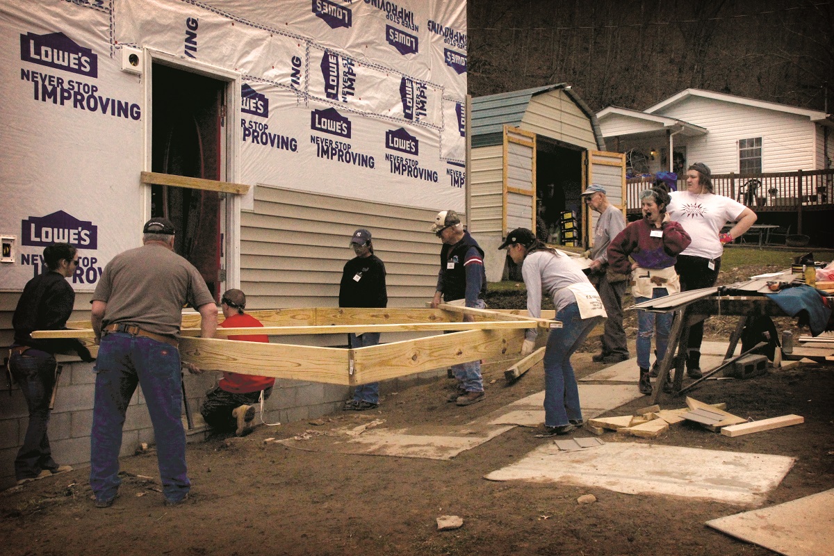 A WorkFest crew lifts the frame for the family's new porch.