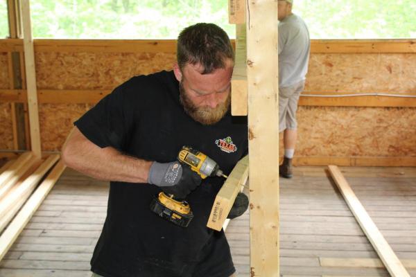 Senior Manager of Community Relations Diania Ciresi (in the green tie dye shirt) and Texas Roadhouse Support Center Employees from Louisville, KY putting together shelves for the new Craft Room at Camp Shawnee.