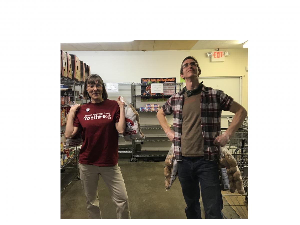 Benny and Kathleen pose with bags of potatoes in CAP's food pantry.