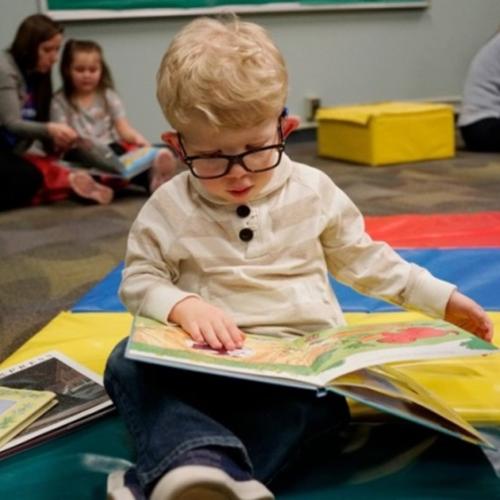 A young boy enjoys a book at the 2022 Books for Kids Kick-Off at the Buffalo Hearing and Speech Center.
